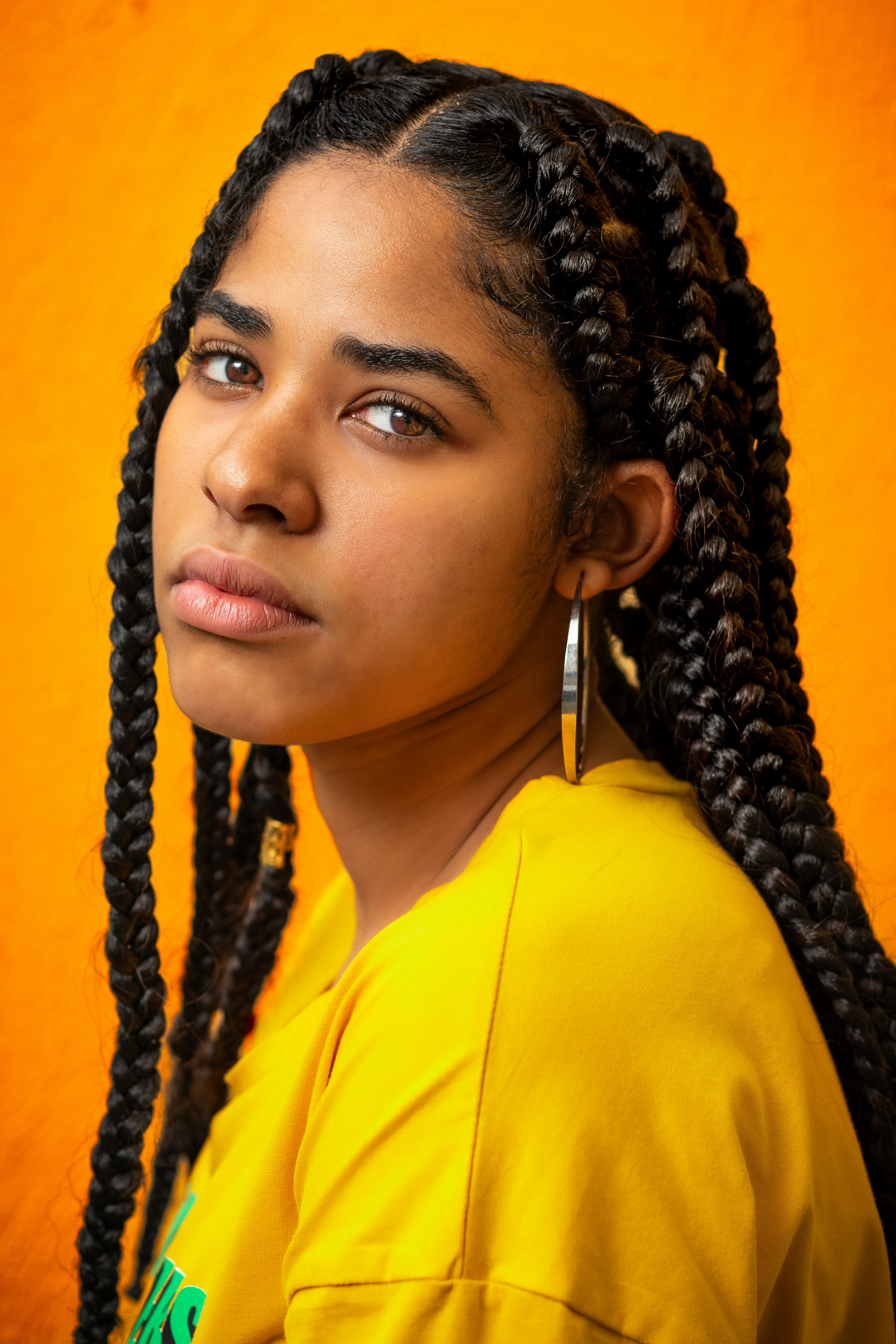 Woman with long black braids in a yellow top